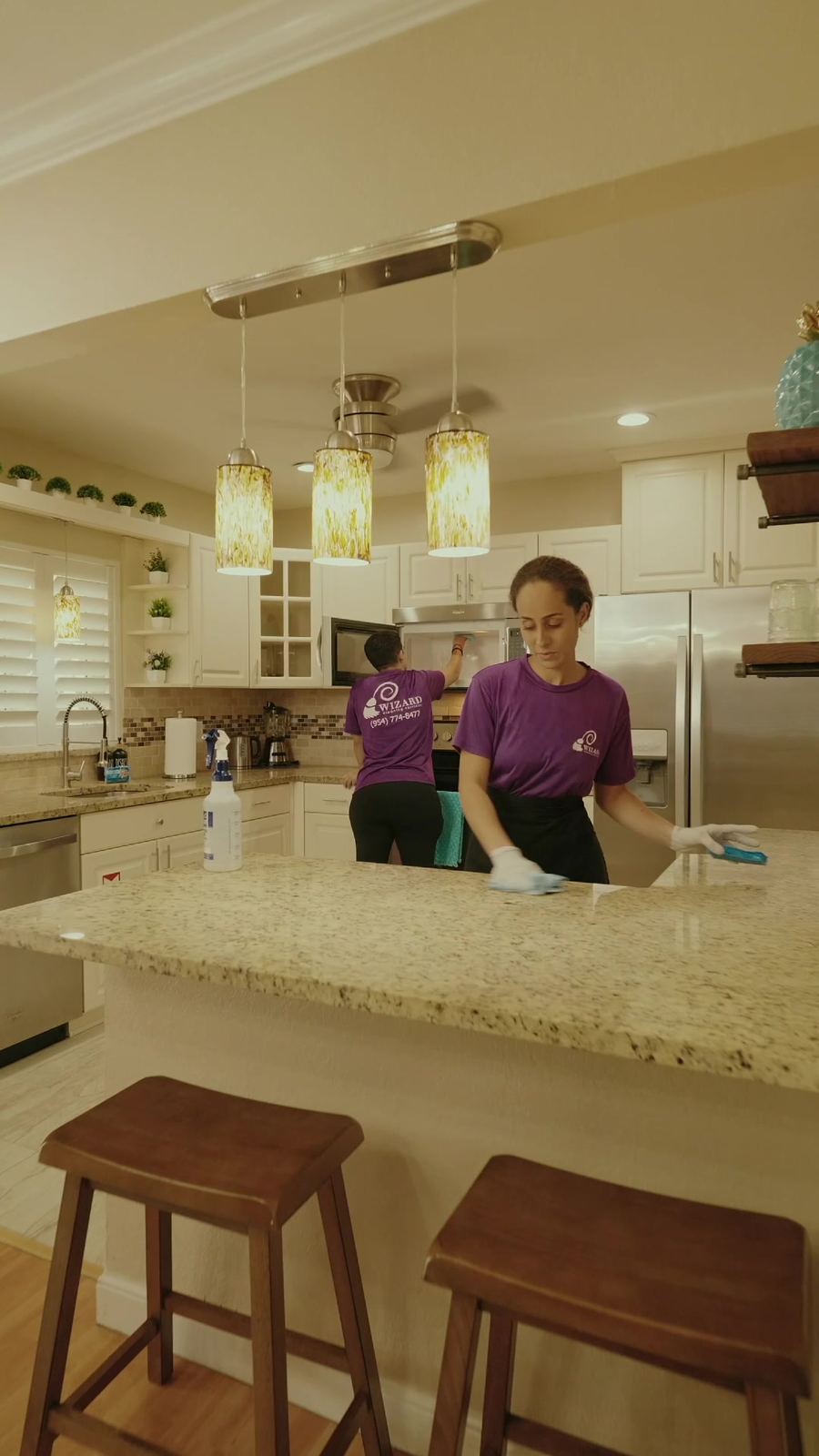 Two Wizard cleaners in purple uniforms cleaning a kitchen
