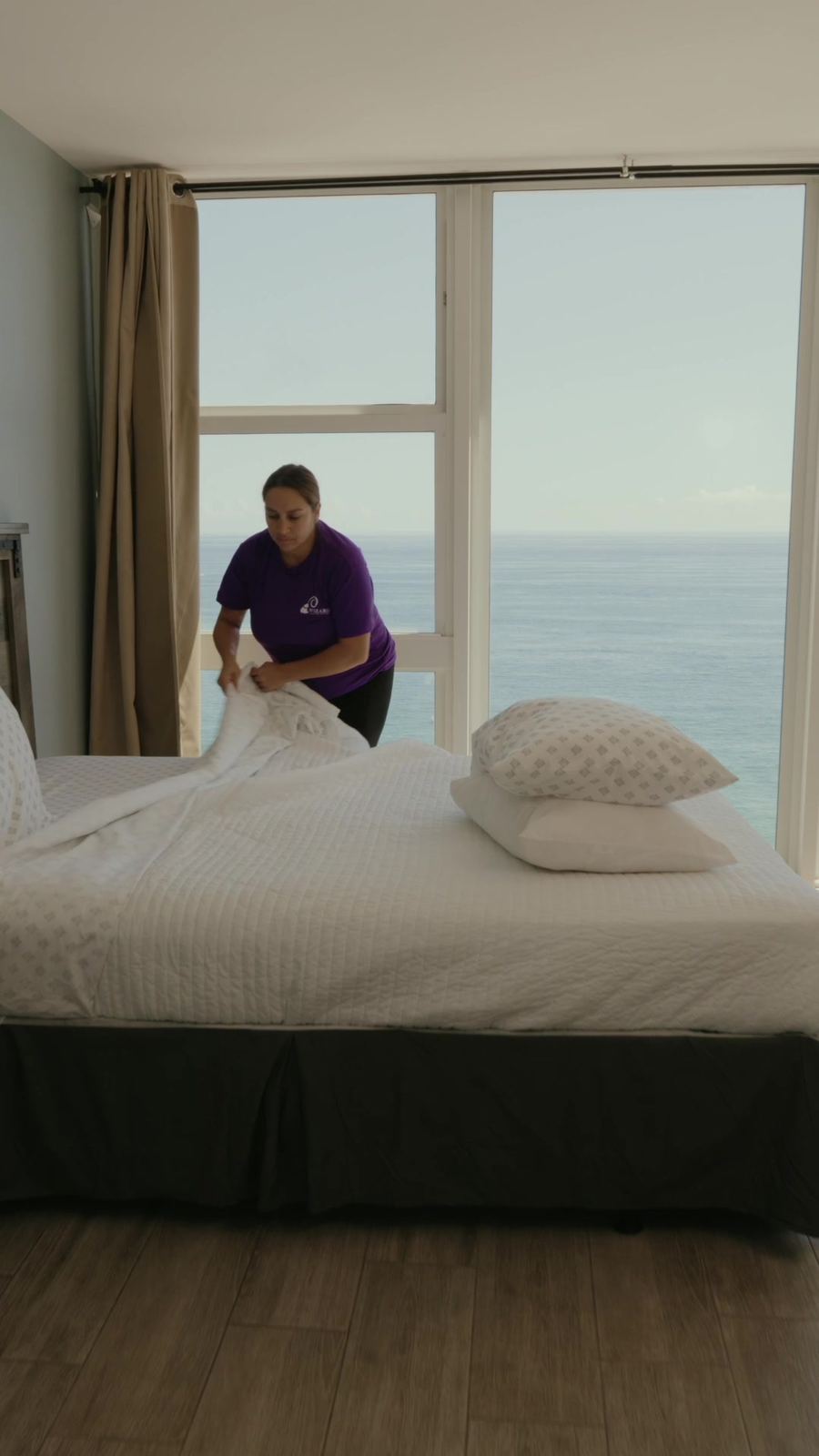 Wizard cleaner making a bed in a vacation rental with an ocean view