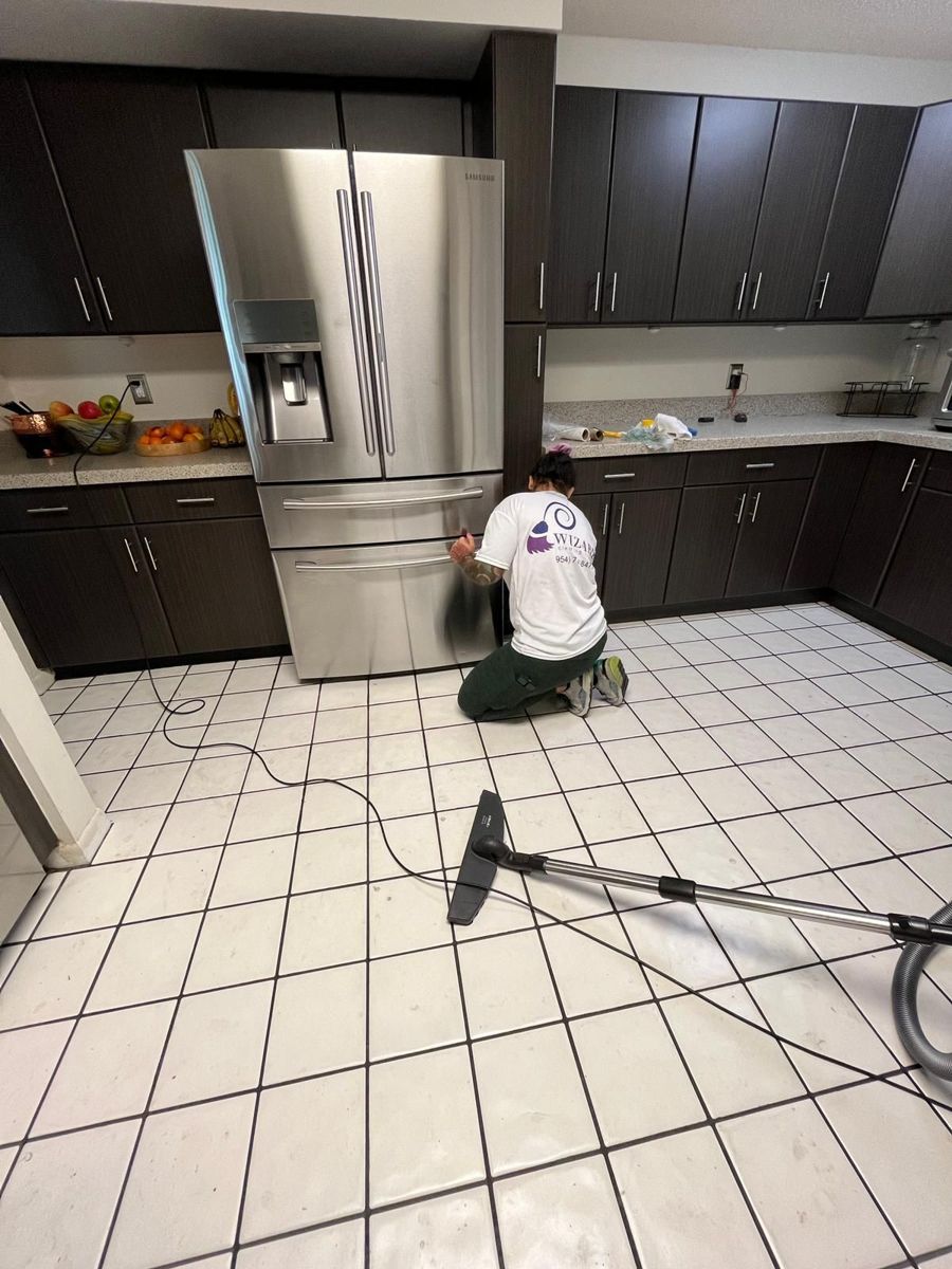 Cleaner washing the floor of an empty kitchen