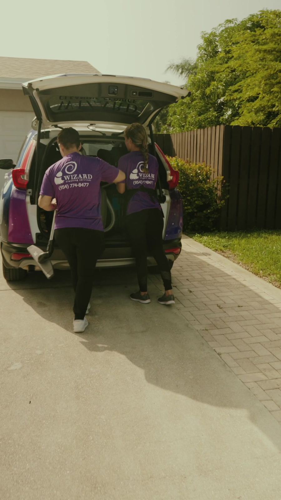Two cleaners unloading equipment from a Wizard car